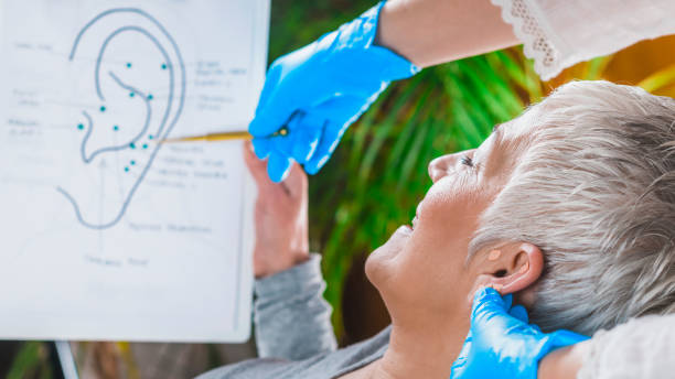 acercamiento de mujer recibiendo tratamiento de auriculoterapia mientras sostiene un mapa en su mano